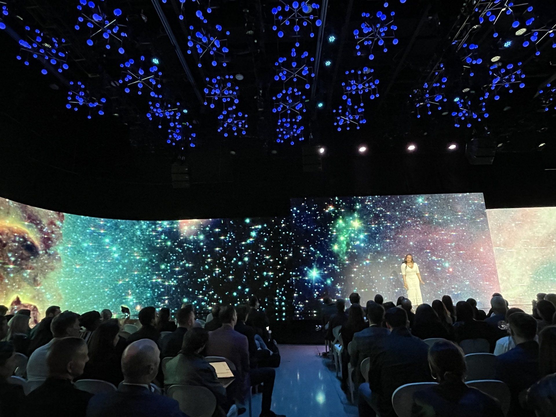 A group of people are sitting in front of a large screen.