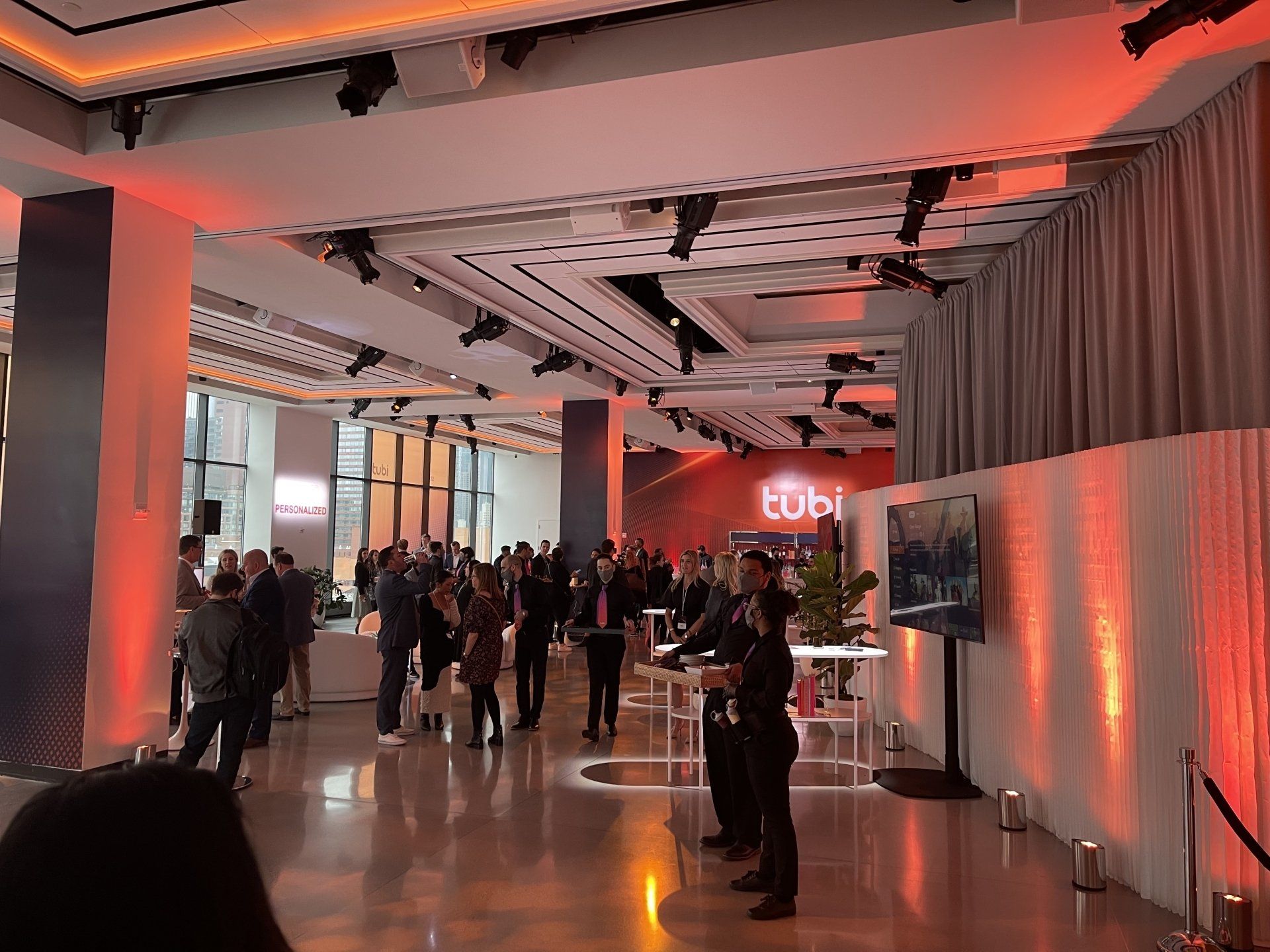 A large room with a lot of people standing around tables.