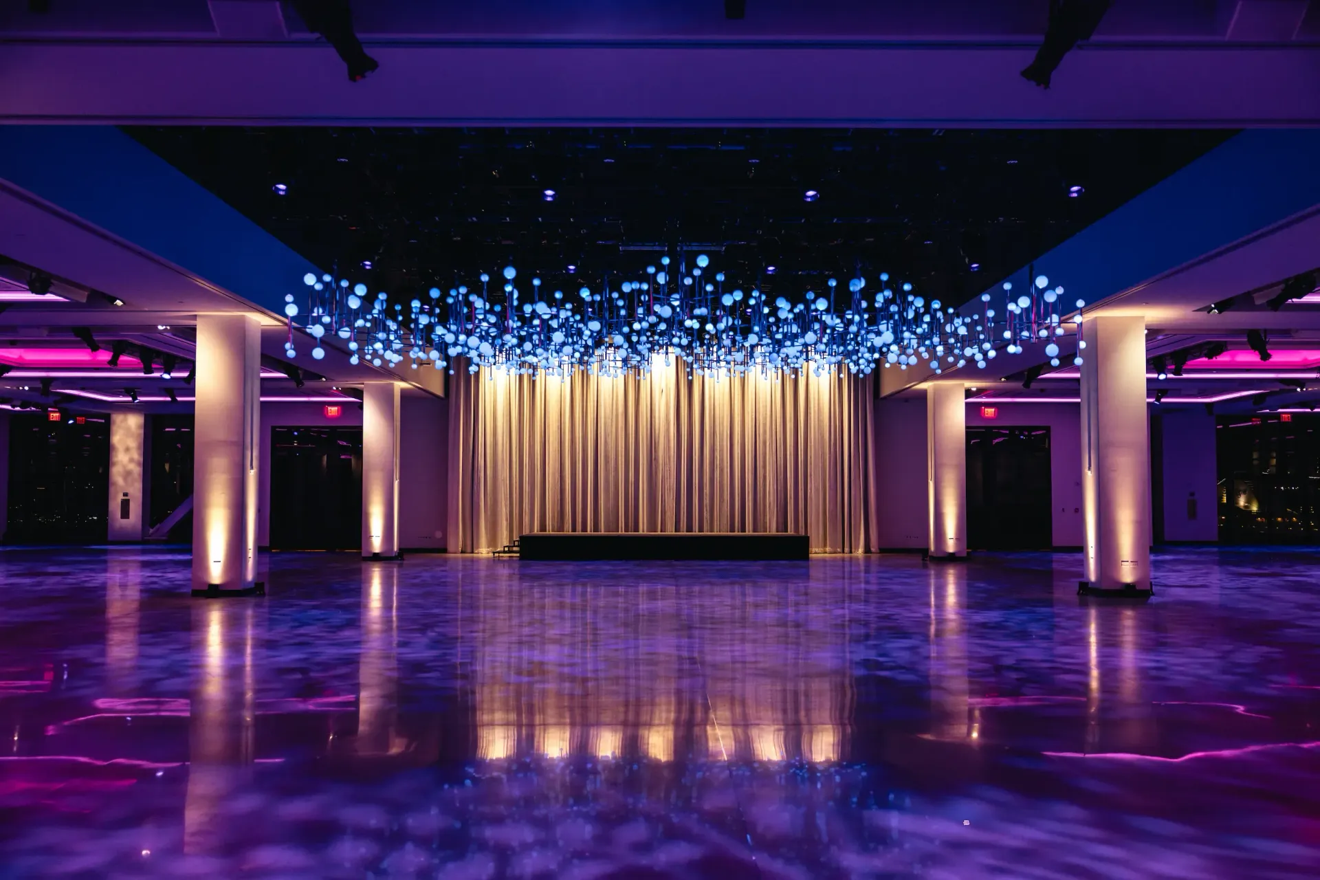 Large event space with stage, lit with purple and blue lights.