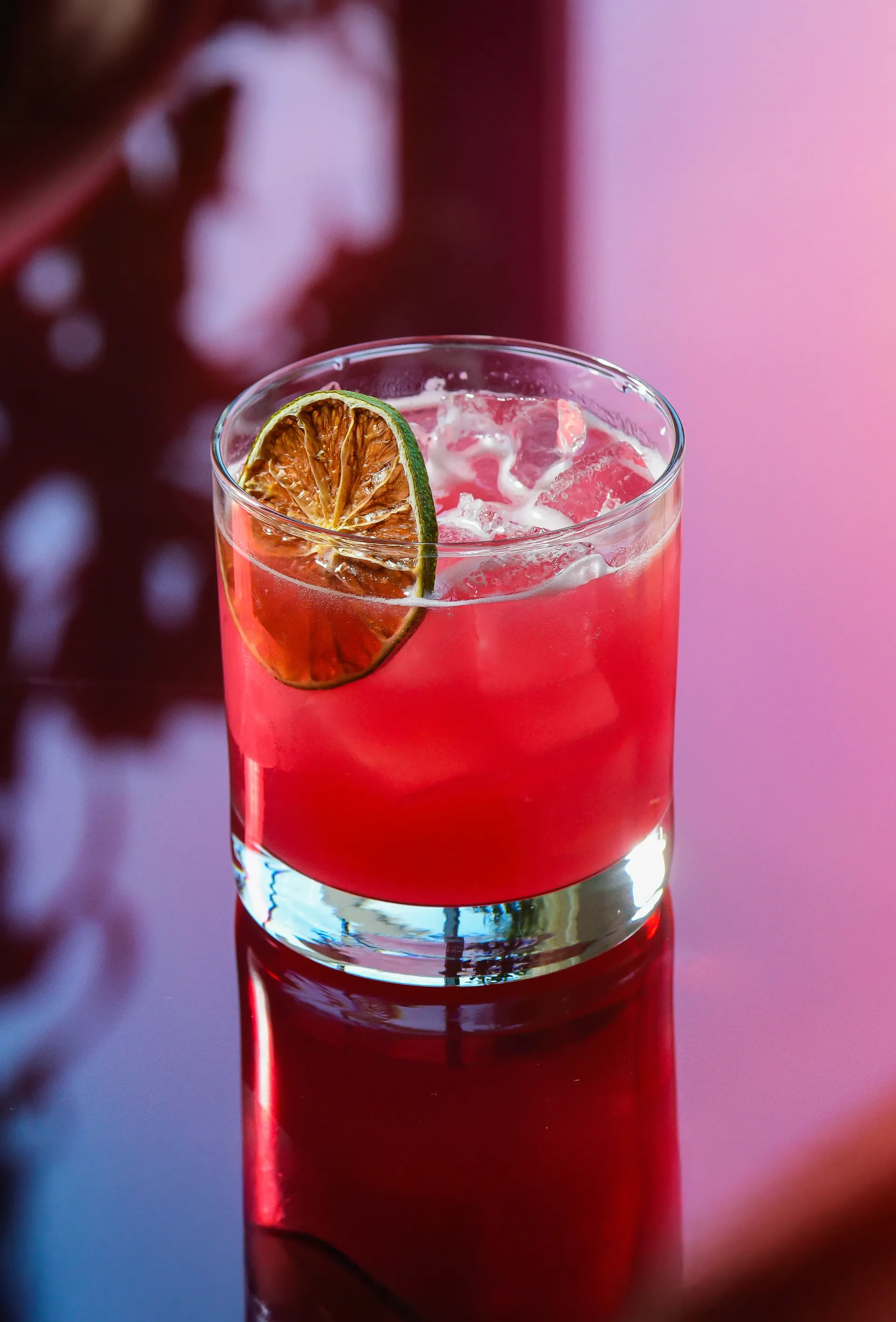 Two glasses of red liquid with ice on a table