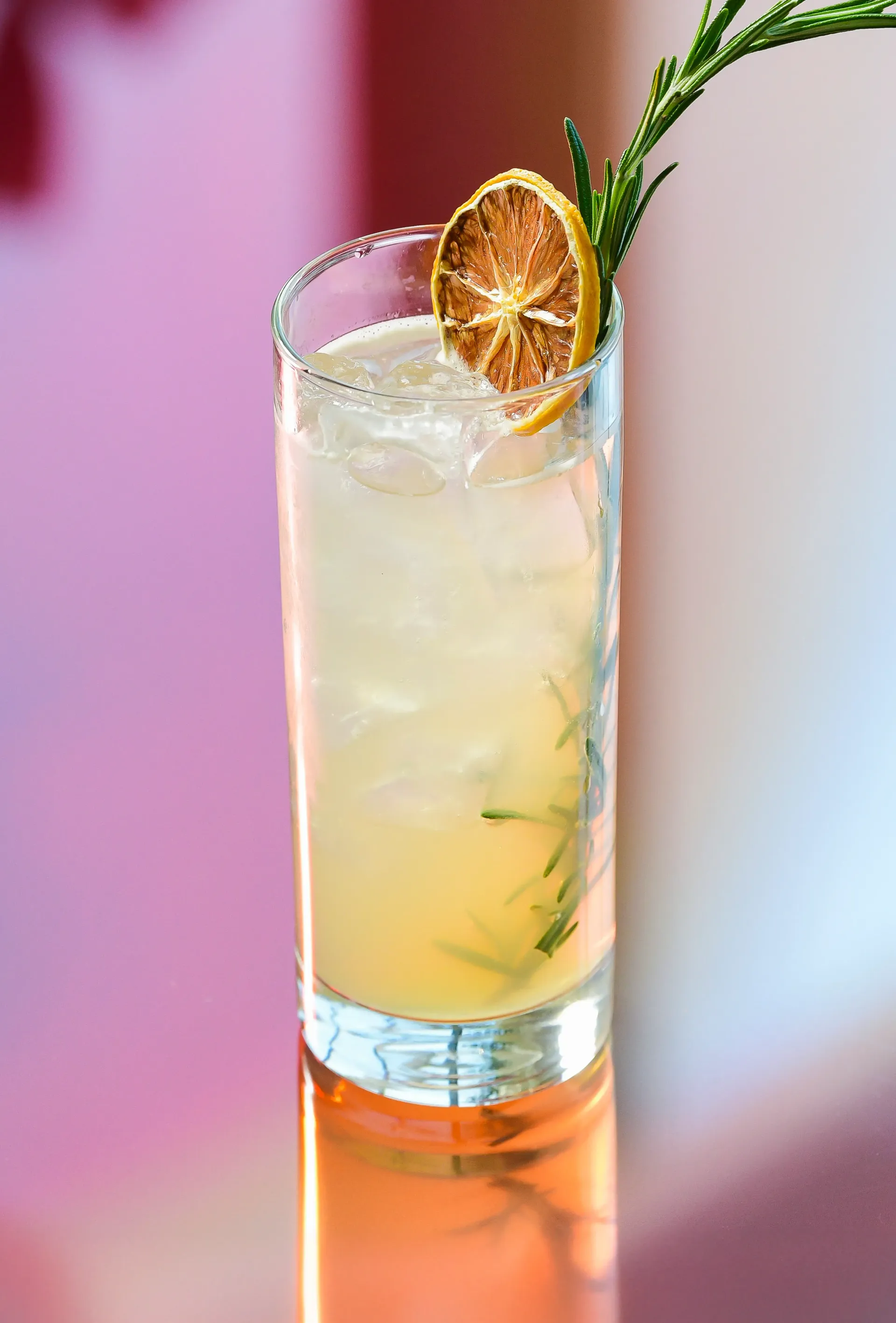 A tall glass filled with ice and a straw on a napkin on a table.