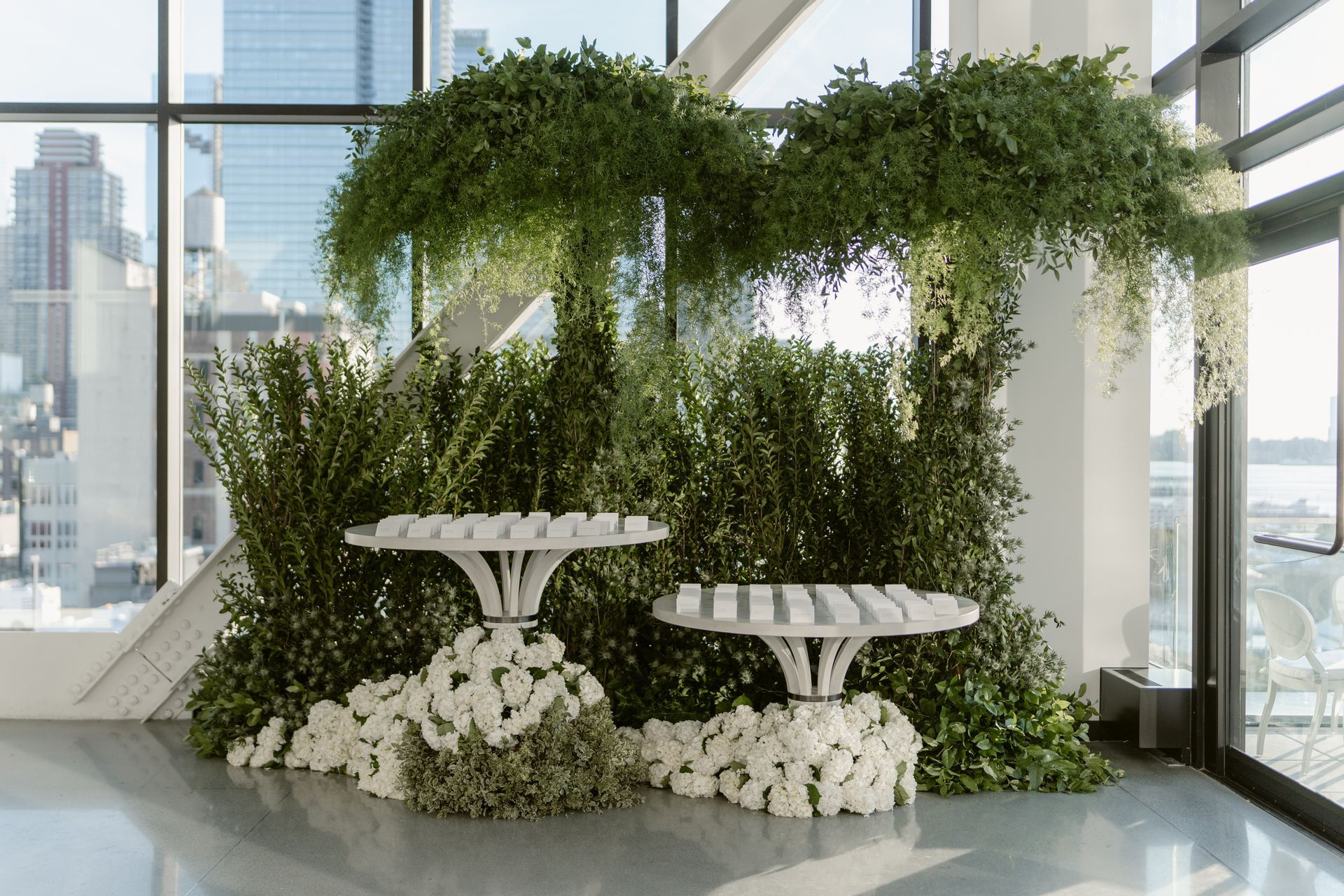 There are two tables in front of a wall covered in plants.