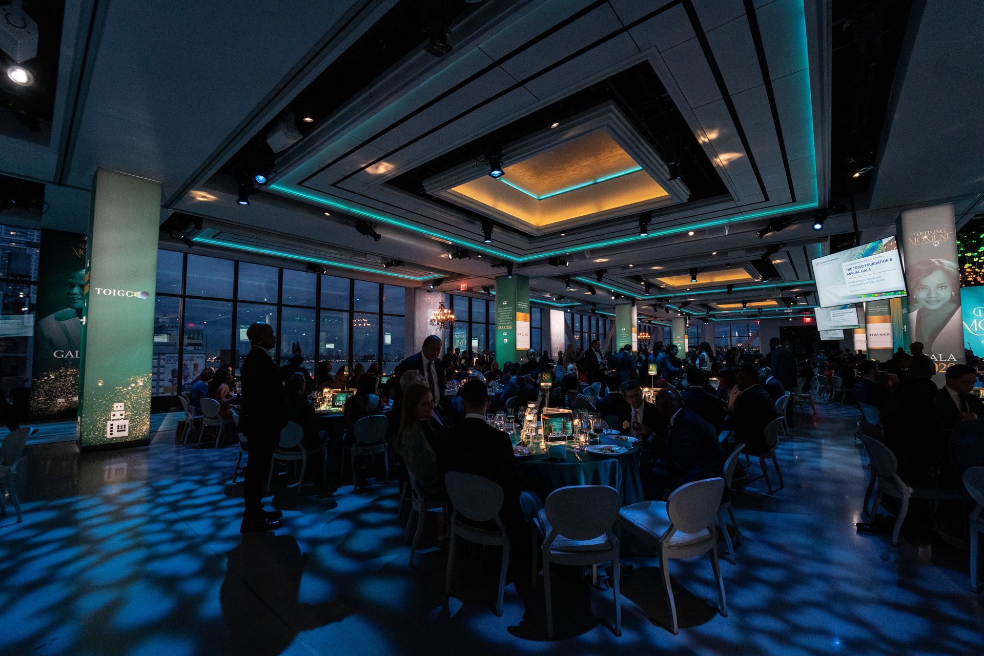 A large room filled with people sitting at tables and chairs.