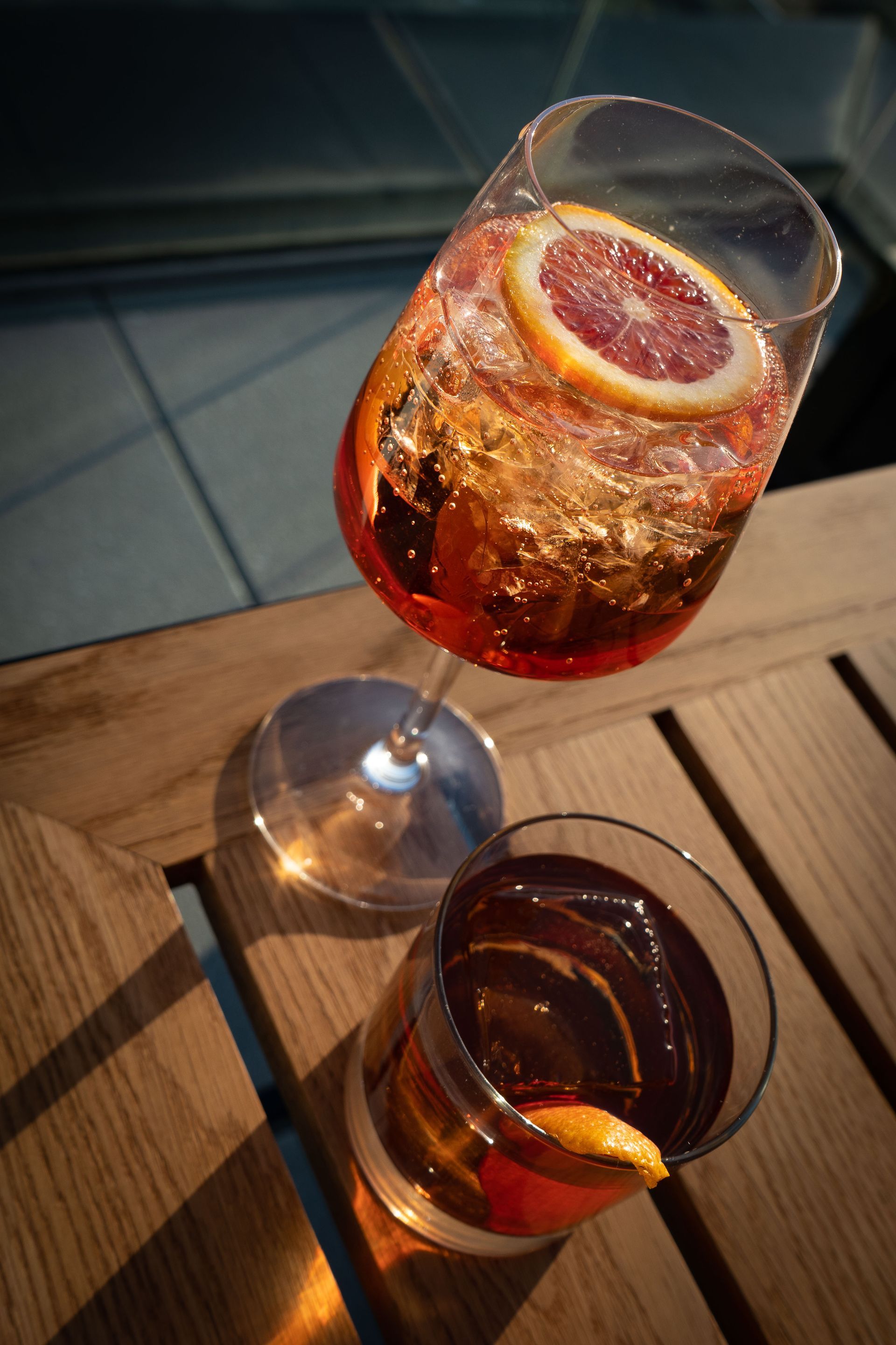 Two glasses of alcohol are sitting on a wooden table.