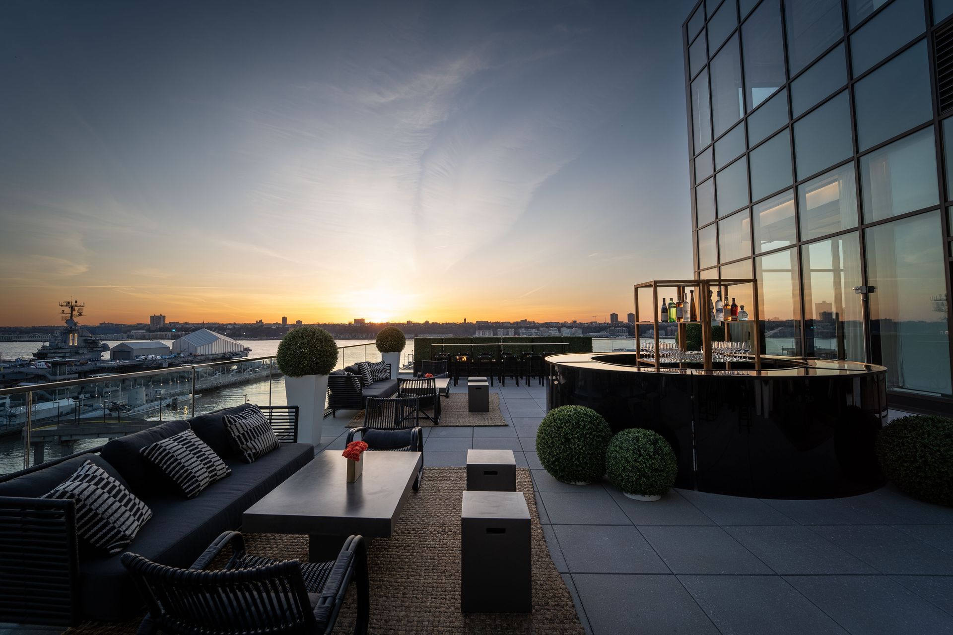 A patio with a couch , table , chairs and a bar at sunset.