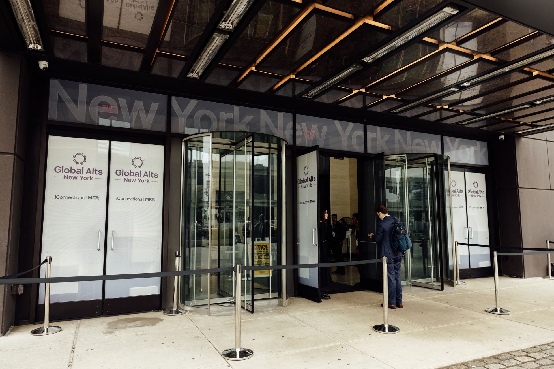 Entrance of a New York building with revolving doors; a person stands outside.