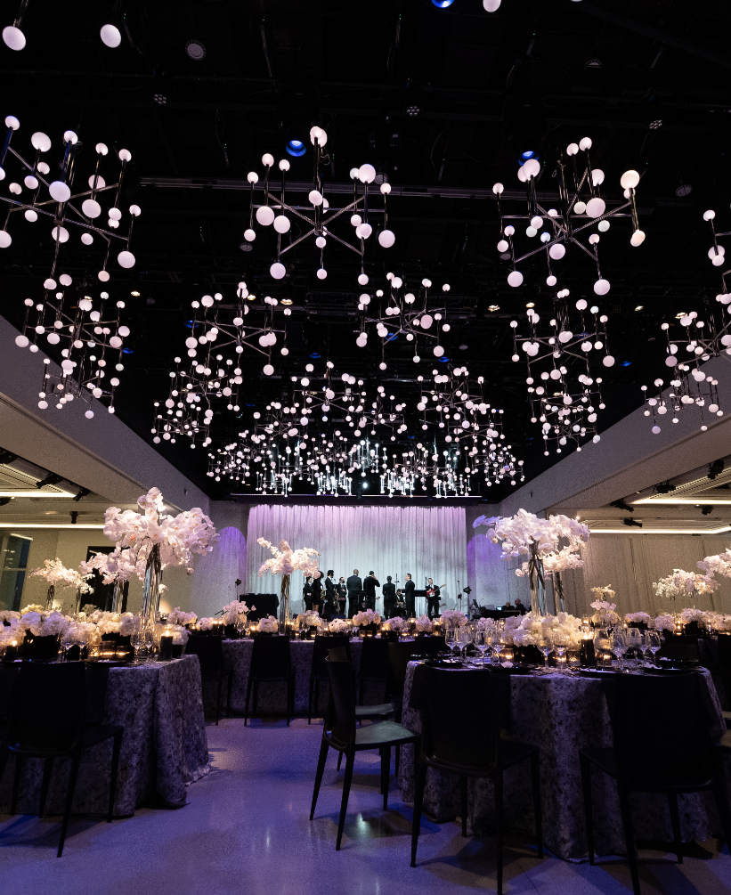 A large room with tables and chairs set up for a wedding reception