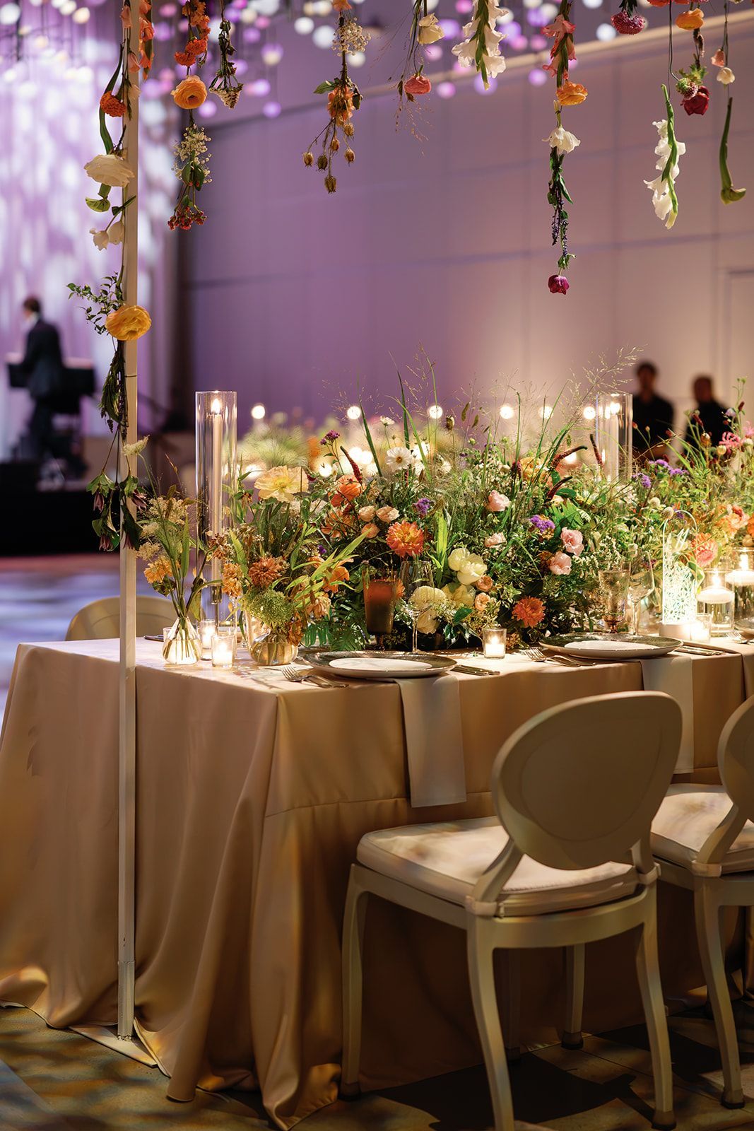 Elegant banquet table with floral centerpiece and hanging decorations in a softly lit reception hall