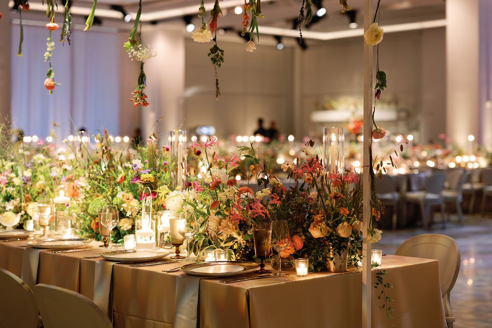 Elegant banquet tables with floral centerpieces and warm string lights in a decorated event hall