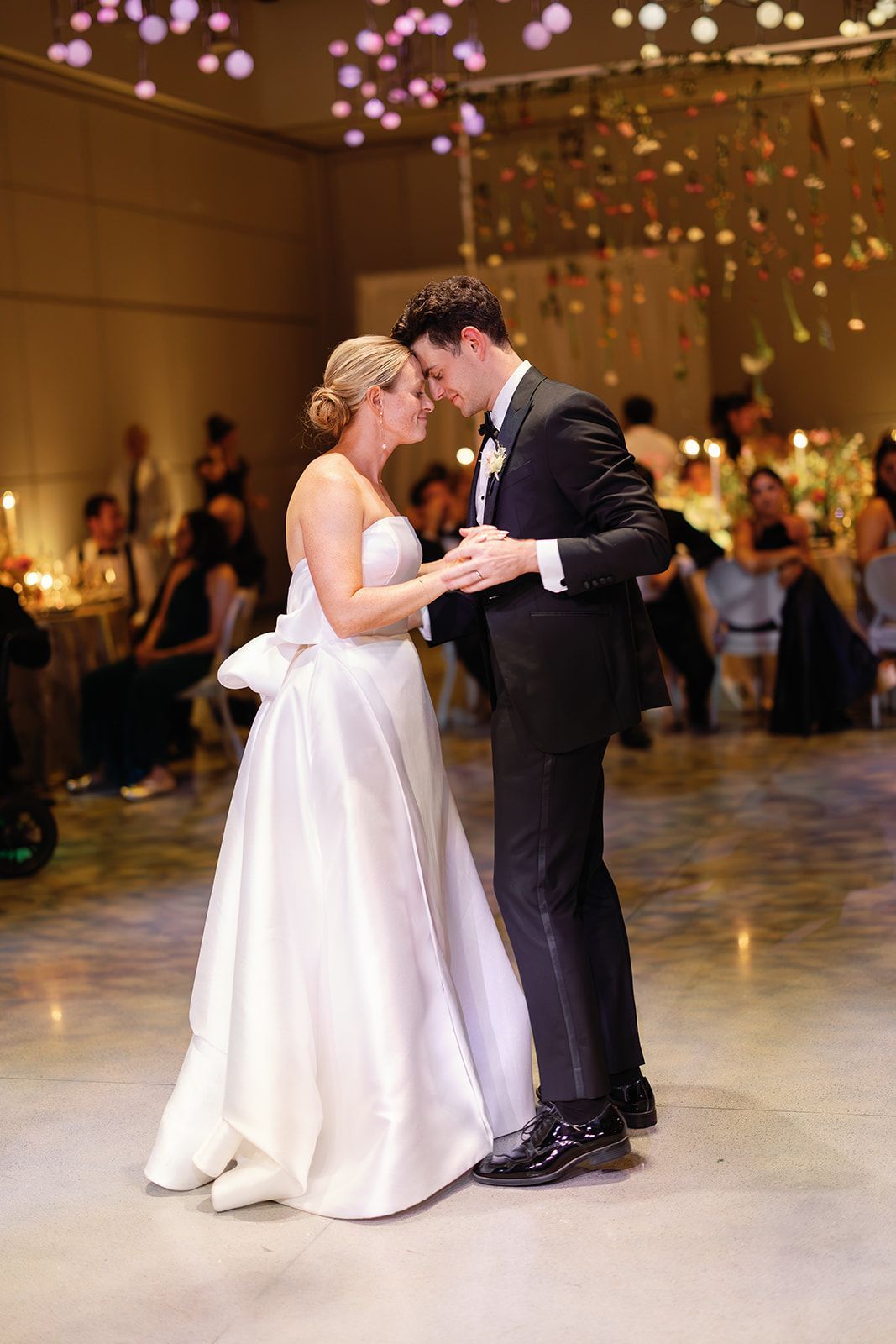 Bride and groom dancing closely at a wedding reception under warm lights