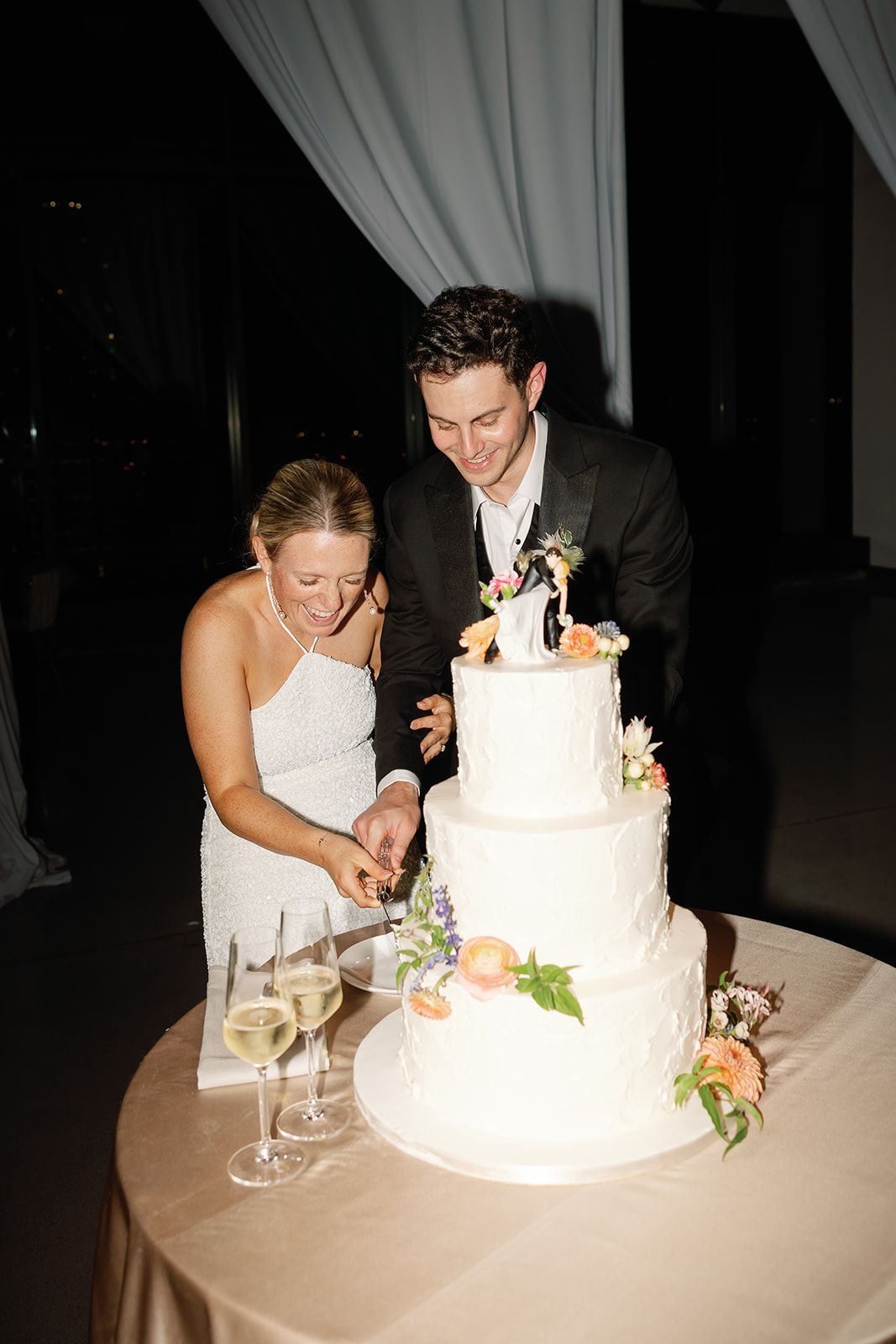 Bride and groom cutting a tiered wedding cake at a reception table