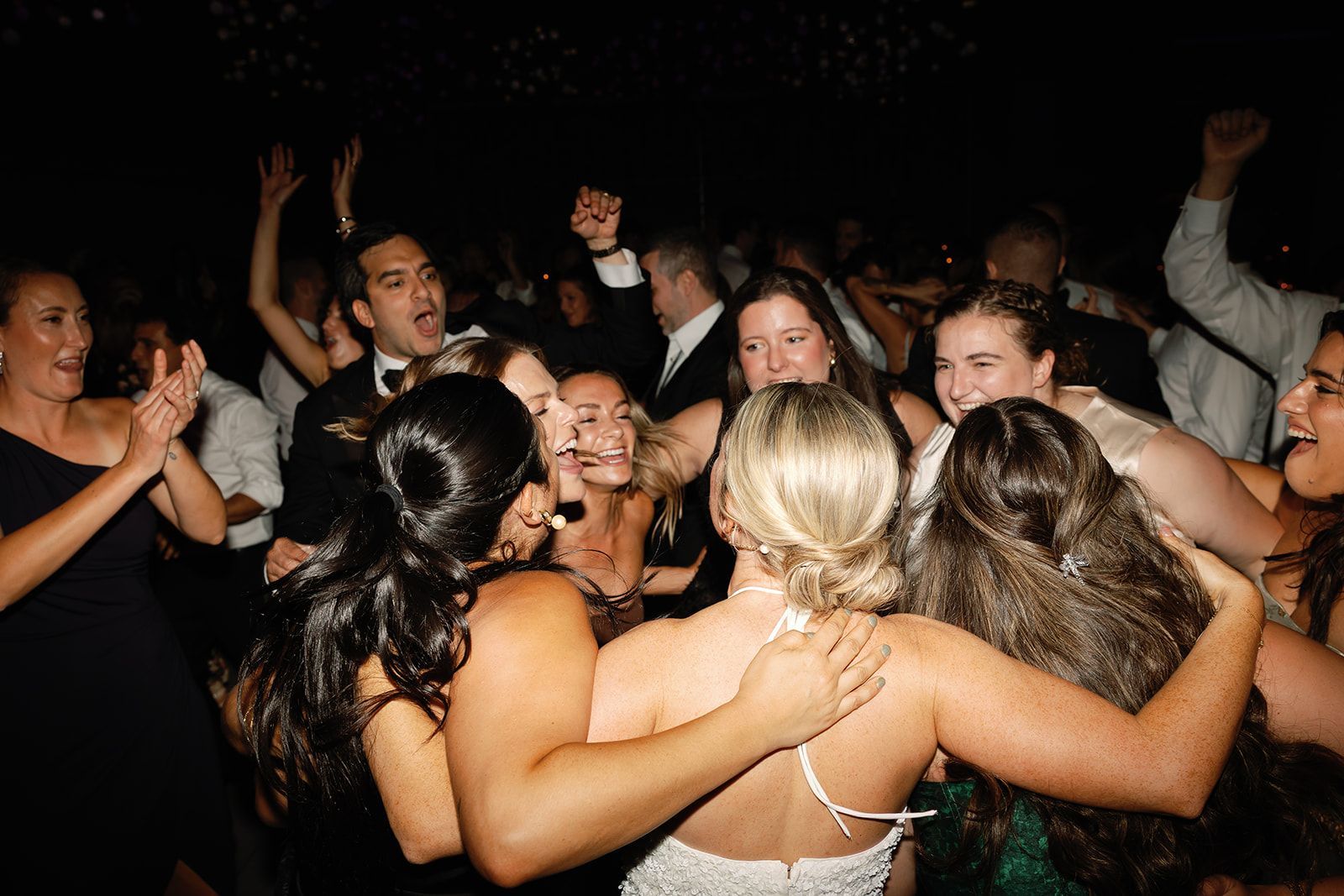 Friends dancing and hugging at a lively party in a dark club-like setting