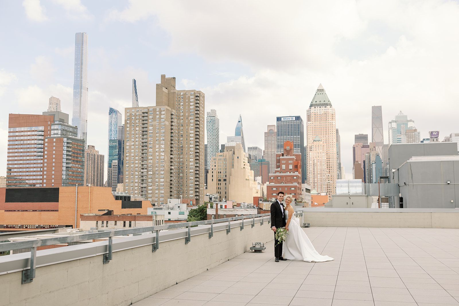 Couple in wedding attire on a rooftop terrace with a city skyline in the background