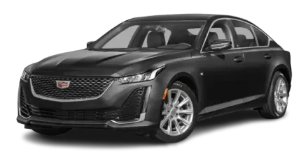 Black Cadillac sedan parked, front angled towards the viewer, gray wheels, cloudy sky.