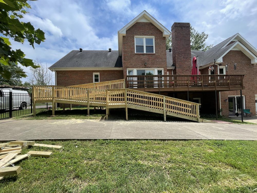 A long wooden accessibility ramp built in front of a brick residential home leading up to an elevated deck.