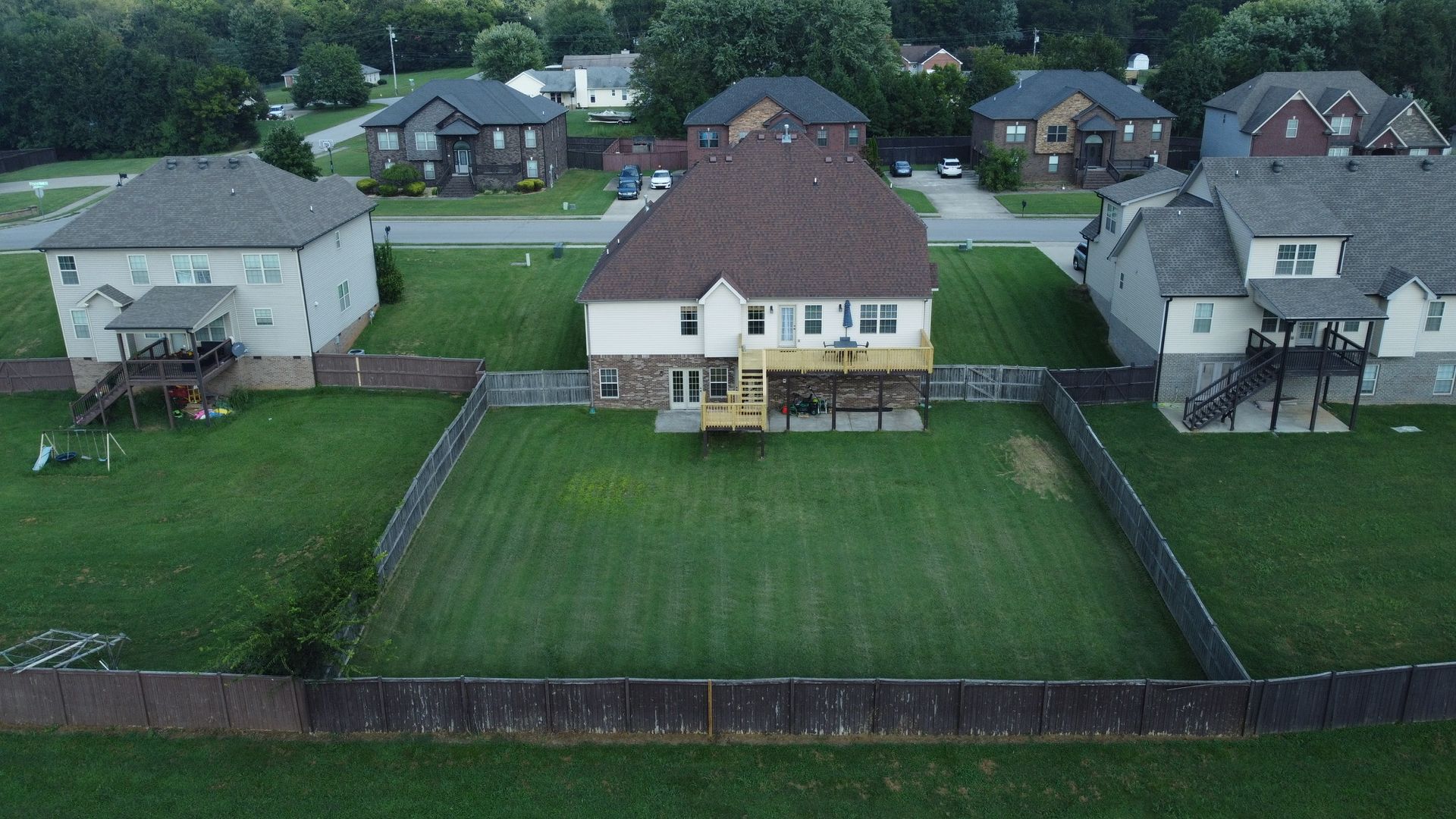 An aerial view of a suburban neighborhood showing houses with fenced backyards and green lawns.