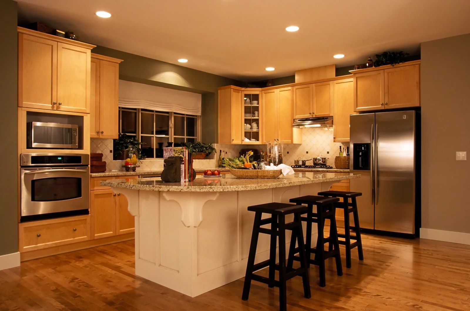 Warm, modern kitchen with wood cabinets, stainless appliances, and a central island with bar stools