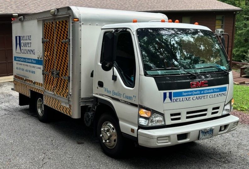 White utility truck with “Maid Service” signage parked in a driveway by a brick house