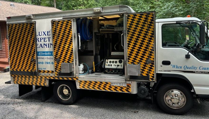 White utility truck with yellow-black chevron panels and open side compartments parked outdoors