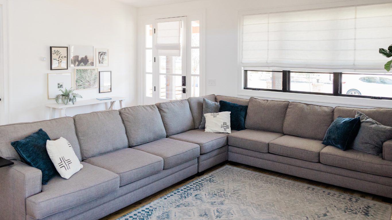 A living room with a large sectional couch and a rug.