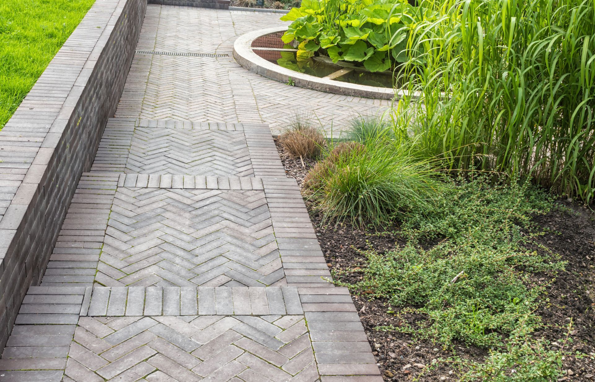 A stoned pathway steps with grass and overlaid tiles.
