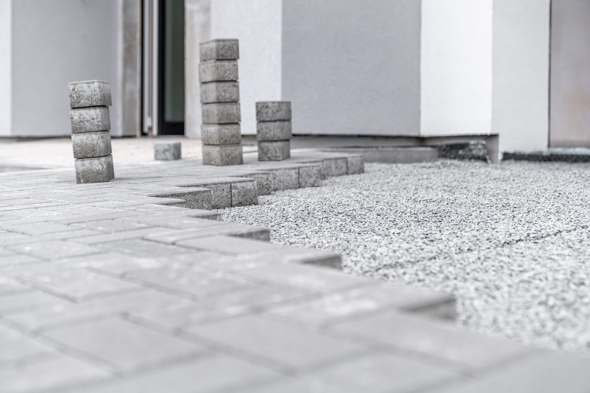 A black and white photo of a brick driveway being built in front of a house.