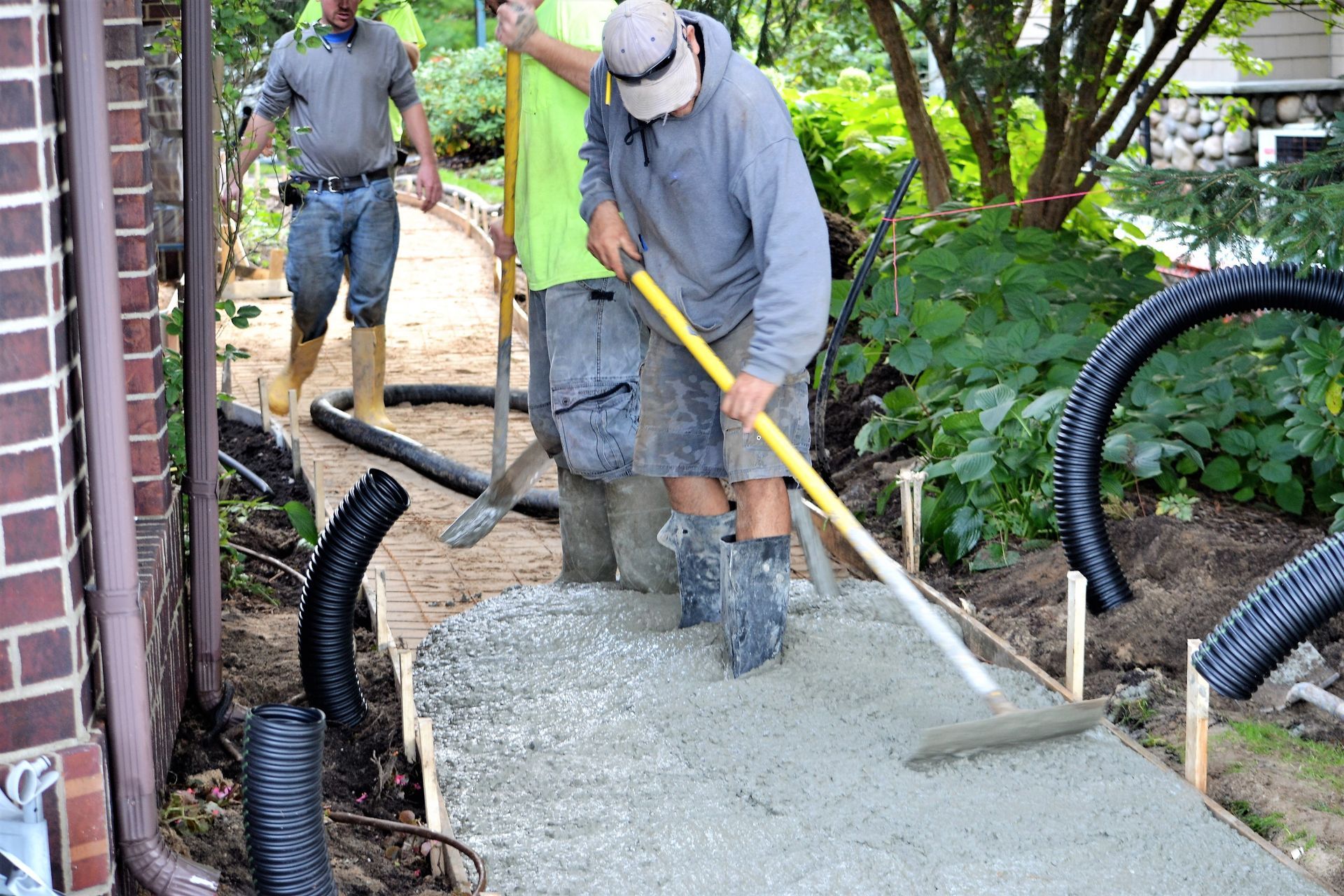 A group of construction workers are working on a sidewalk.