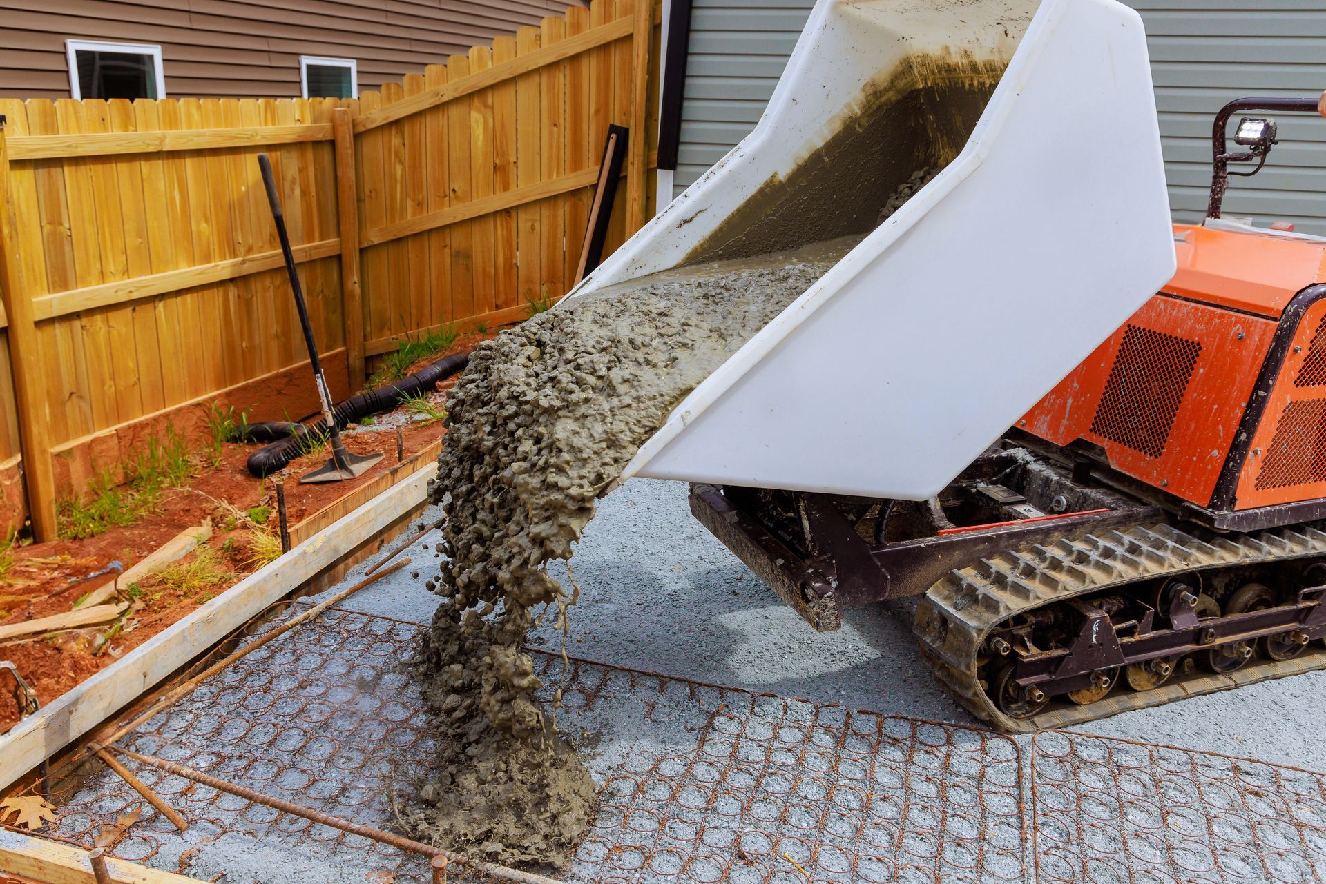A dump truck is pouring concrete into a driveway.