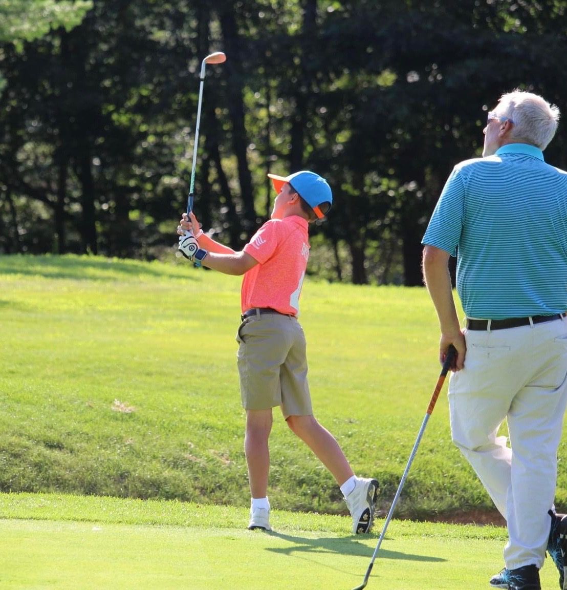 A man and a boy are playing golf on a green