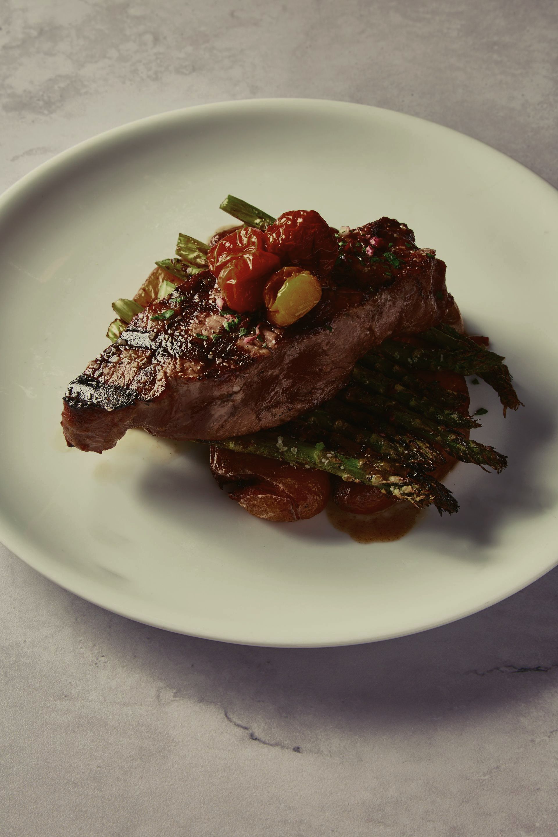 A white plate topped with a piece of meat and vegetables