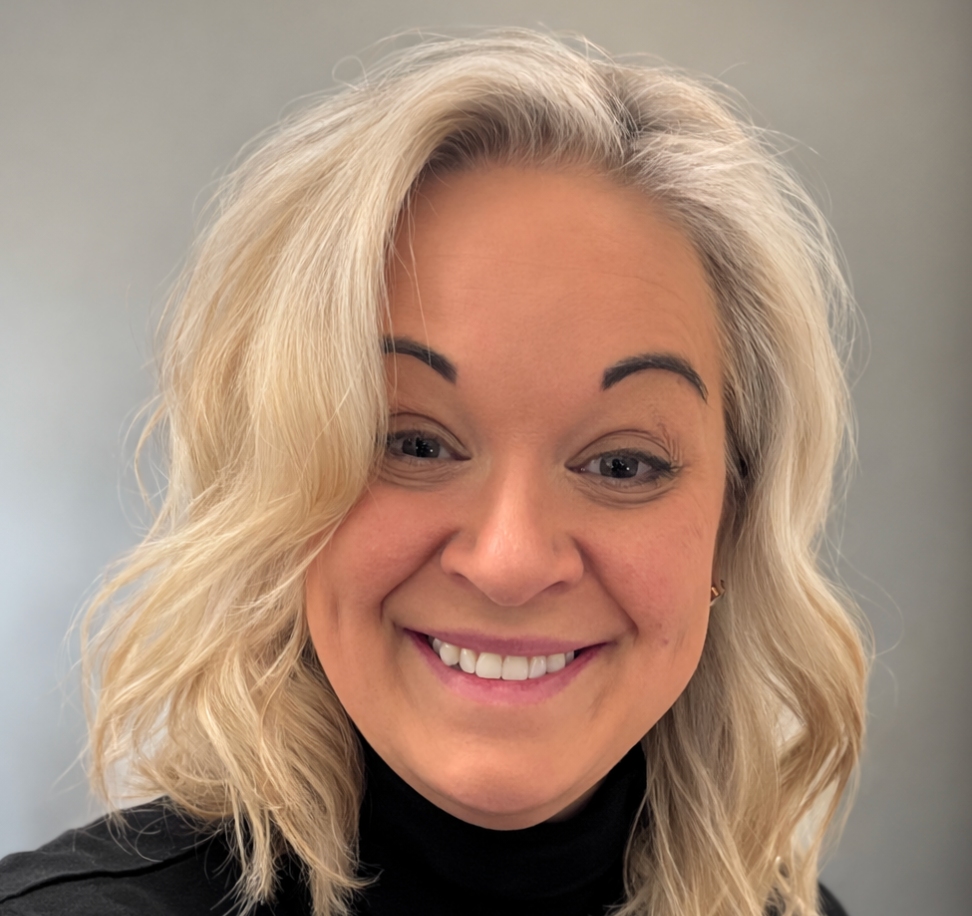 A woman wearing a grey sweater is smiling for the camera