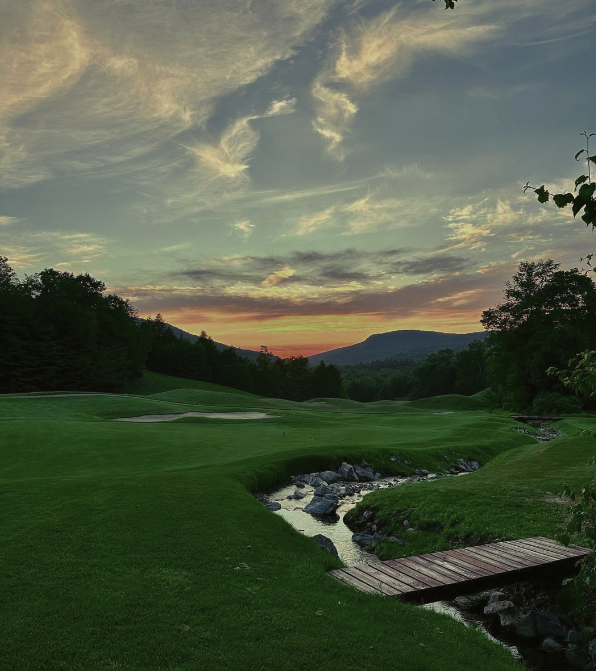 A wooden bridge over a stream on a golf course