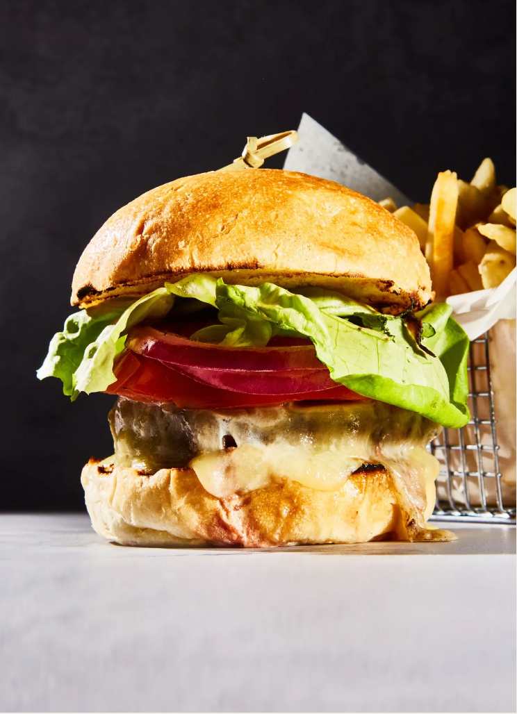 A hamburger is sitting on a table next to a basket of french fries.