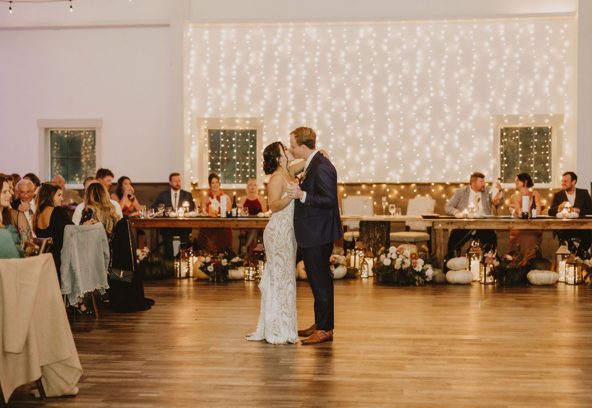 A bride and groom are kissing during their first dance at their wedding reception.