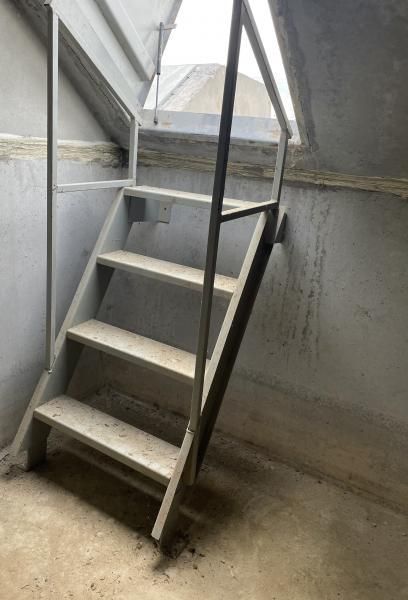Narrow concrete stairway with metal railings in an unfinished interior space