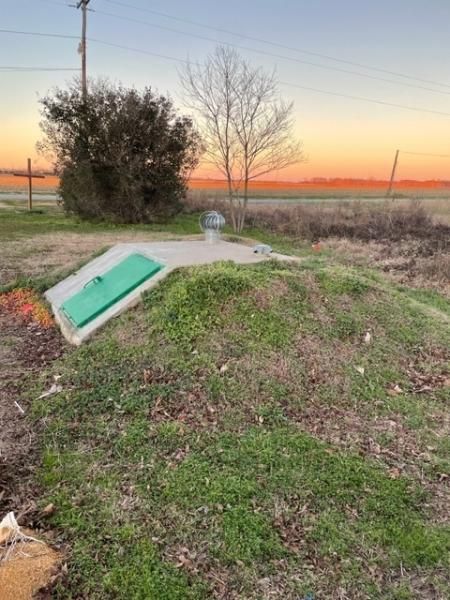 Small grassy mound with a tilted turquoise panel at sunset in a rural field