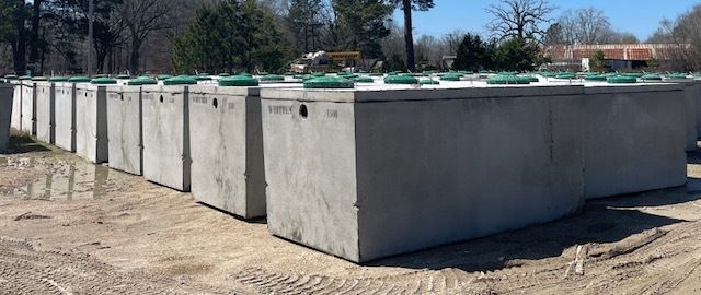 Large concrete storage bins outdoors under bright sunlight, with green covers on top.
