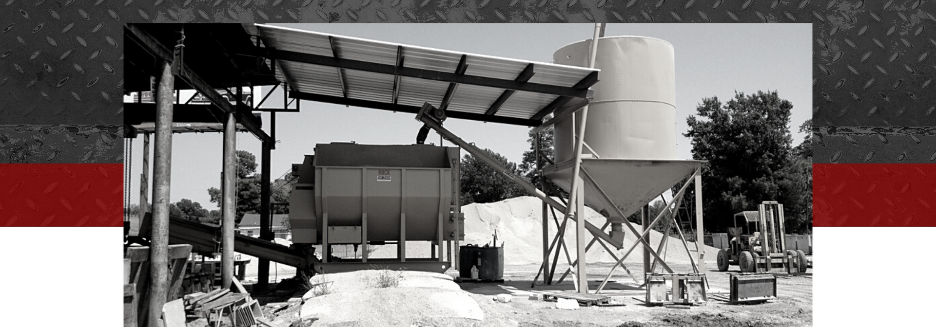 Industrial metal structure under construction with a corrugated roof, tanks, and scaffolding in a yard