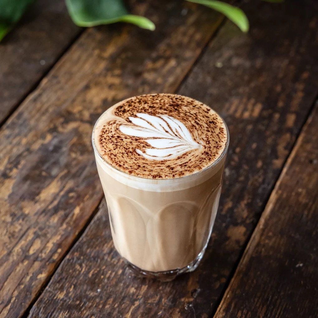 Latte With Latte Art In A Clear Glass On A Rustic Wooden Table — Everyday Interiors in Helensburgh, NSW