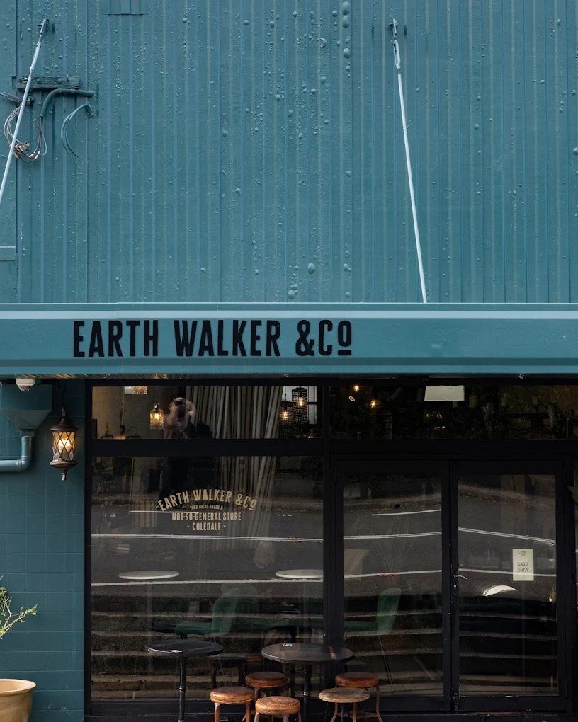 Teal Storefront Of Earth Walker & Co With Dark Windows And Outdoor Tables — Everyday Interiors in Helensburgh, NSW