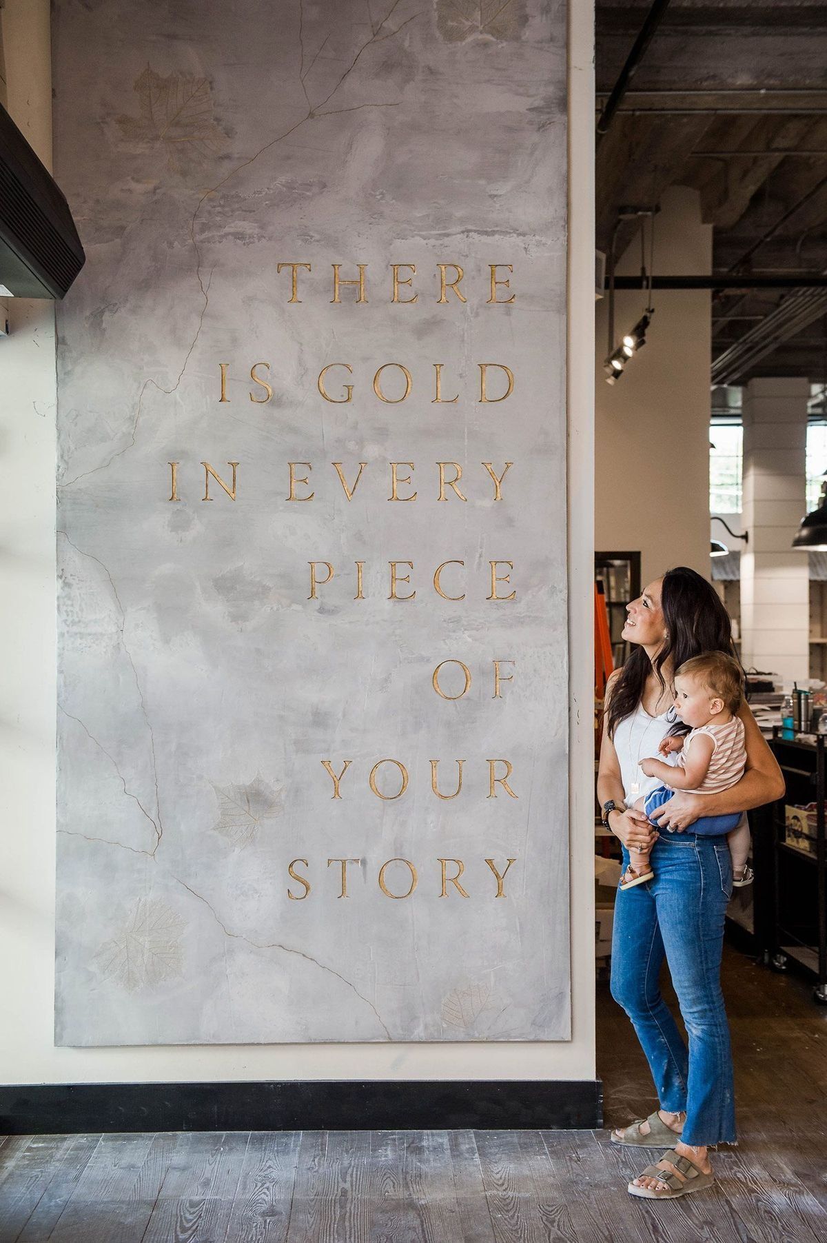Woman Holding A Child Beside A Wall With Gold Lettering In A Cafe — Everyday Interiors in Helensburgh, NSW