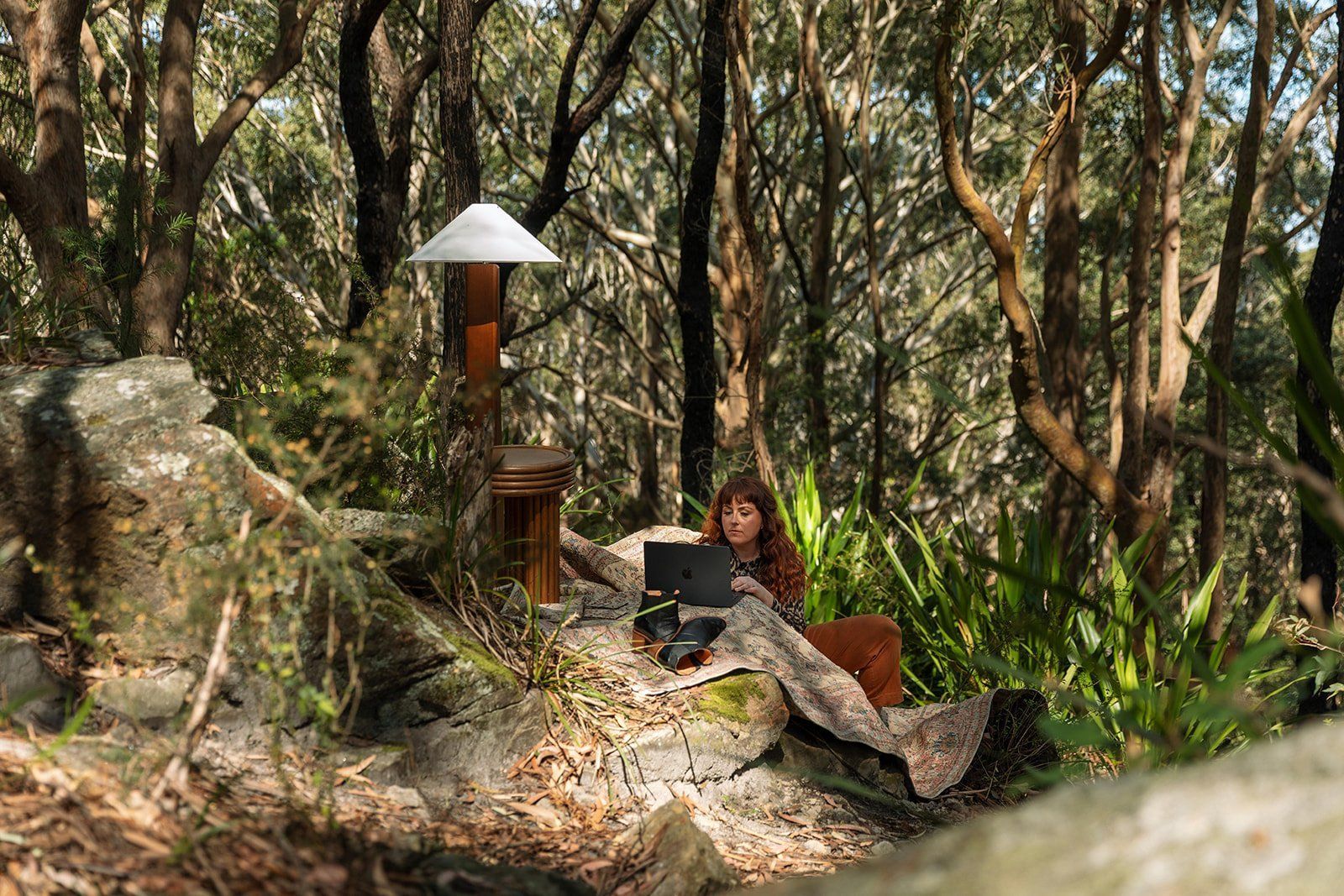 Person Sitting On A Rocky Forest Path Beside A Lantern — Everyday Interiors in Helensburgh, NSW