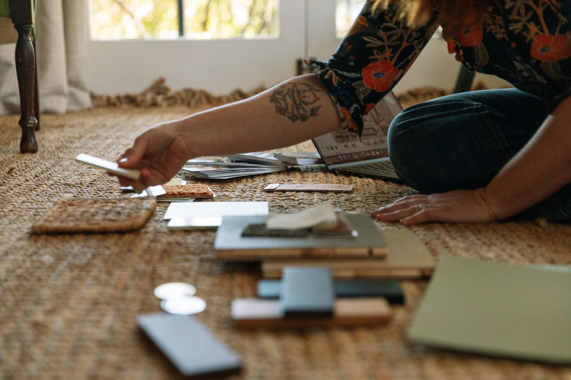 Person Arranging Small Items On A Woven Rug Near A Sunlit Window — Everyday Interiors in Helensburgh, NSW