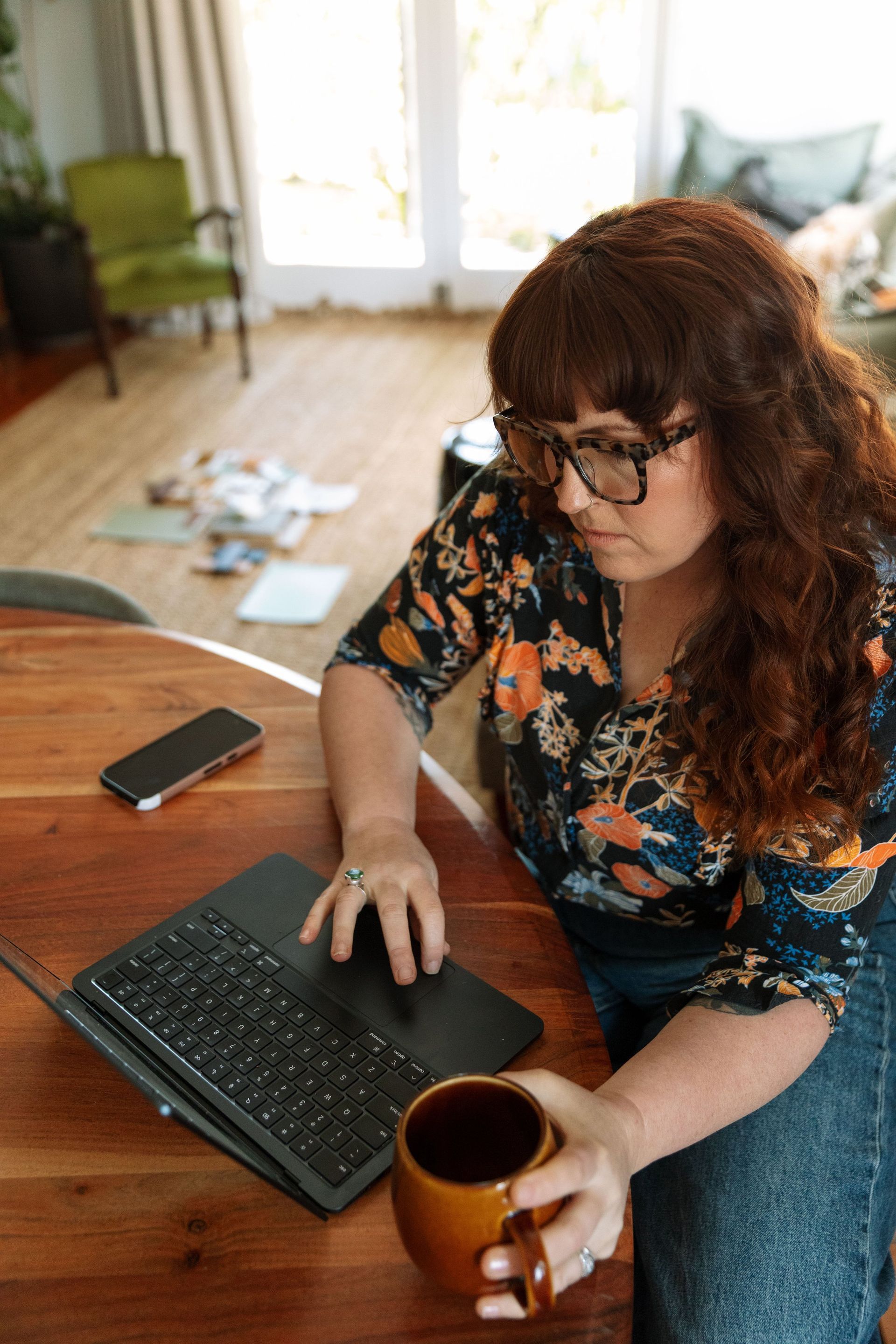 Person Using A Laptop While Holding A Mug At A Wooden Table — Everyday Interiors in Helensburgh, NSW