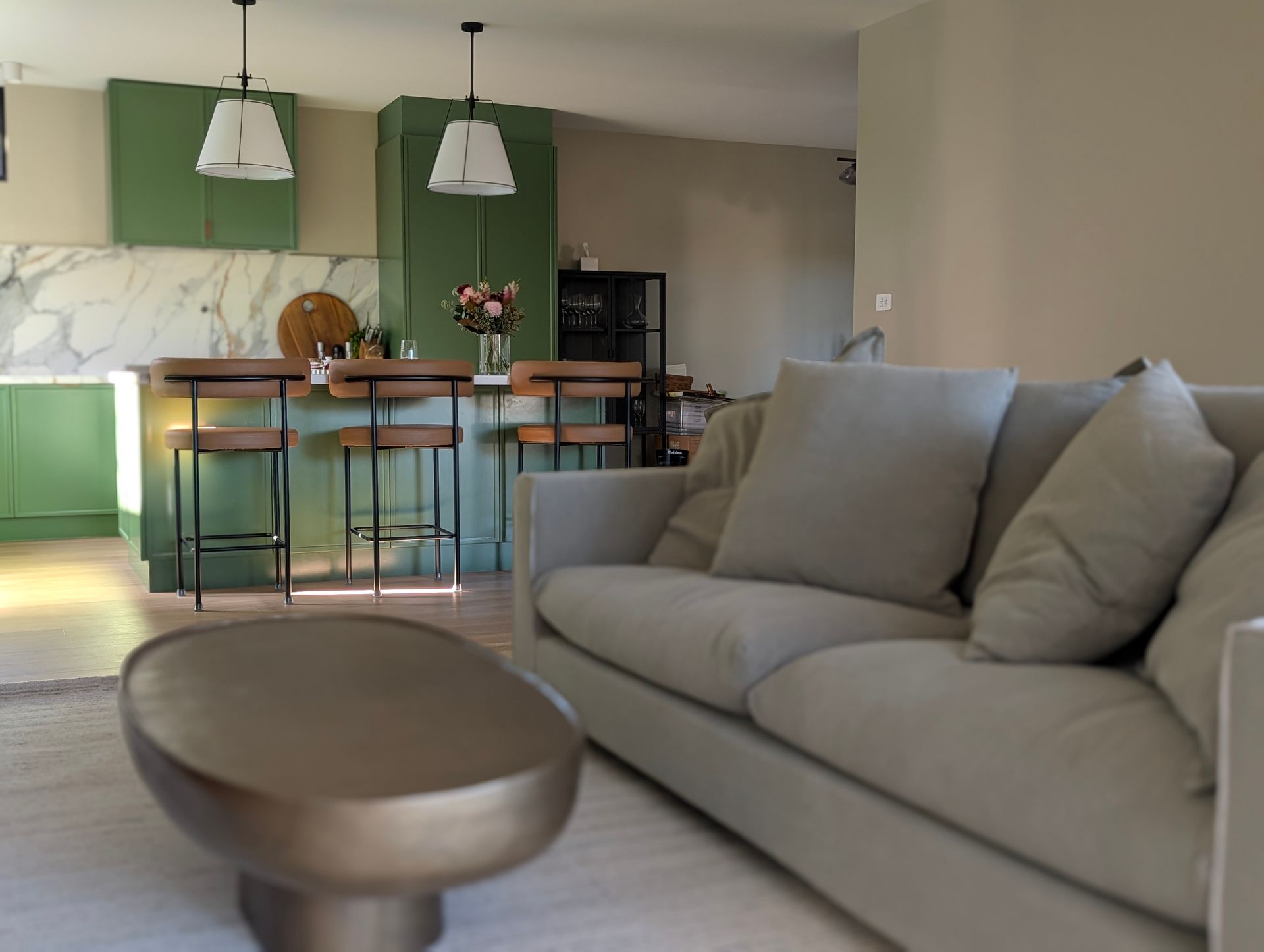 Modern living room with a gray sofa, round coffee table, and green kitchen area in the background — Everyday Interiors in Helensburgh, NSW
