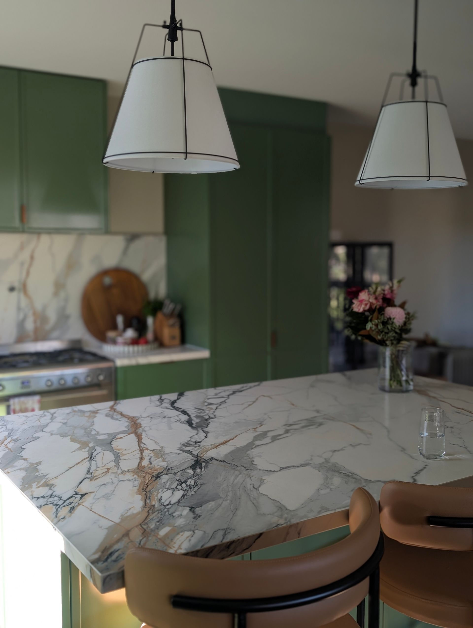 Modern kitchen with green cabinets, marble island, and two hanging pendant lights — Everyday Interiors in Helensburgh, NSW