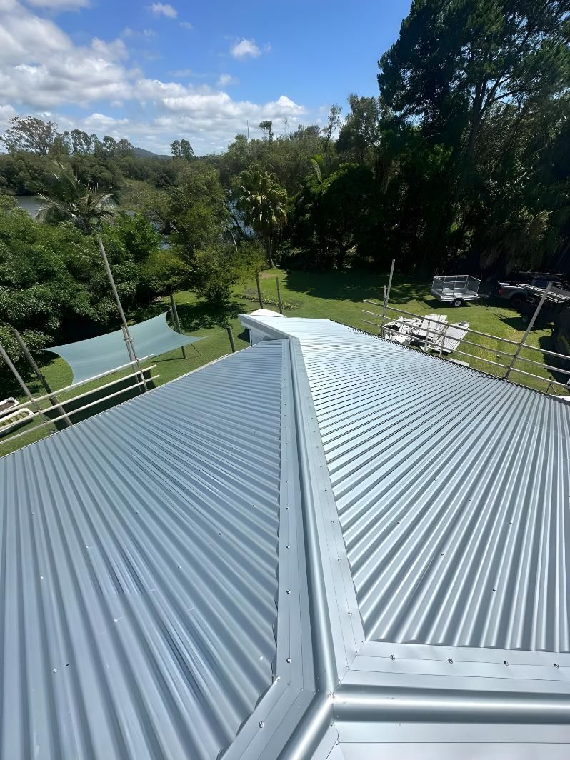 A Close Up Of A Metal Roof With Trees In The Background — Premier Roofing Solutions In Mullumbimby, NSW