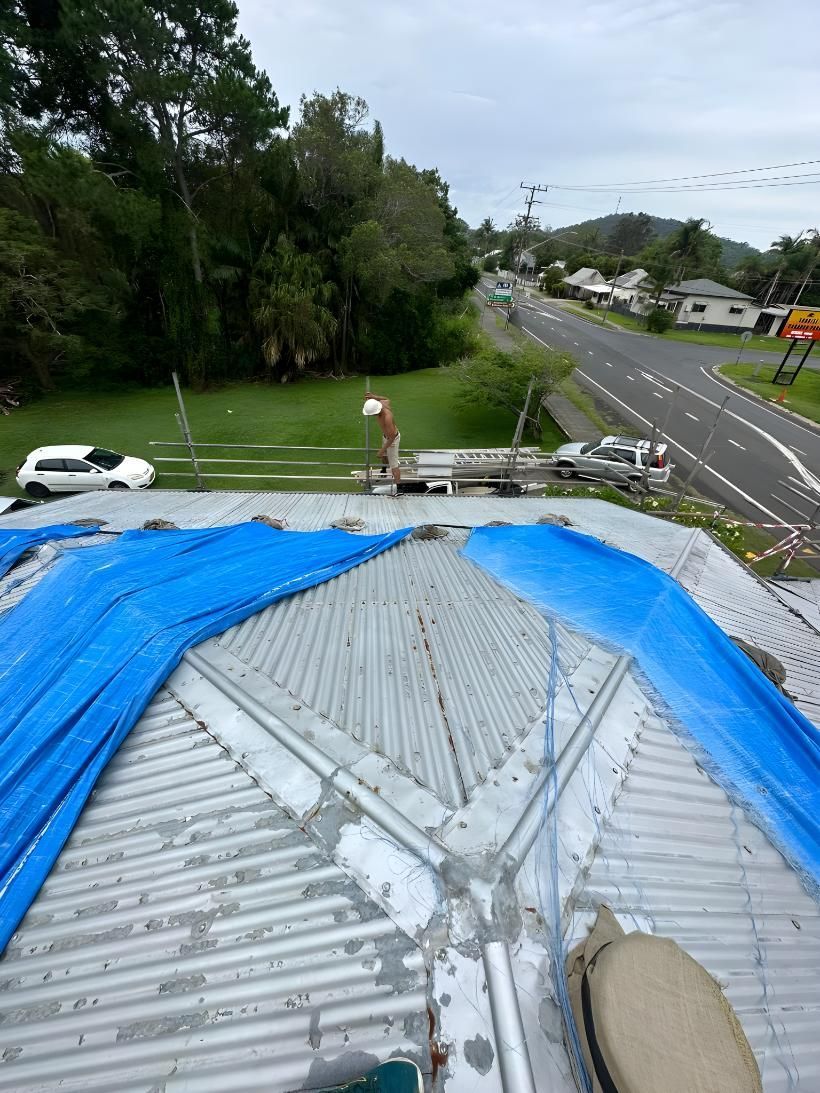 A Blue Tarp Is Covering The Roof Of A Building — Premier Roofing Solutions In Bangalow, NSW