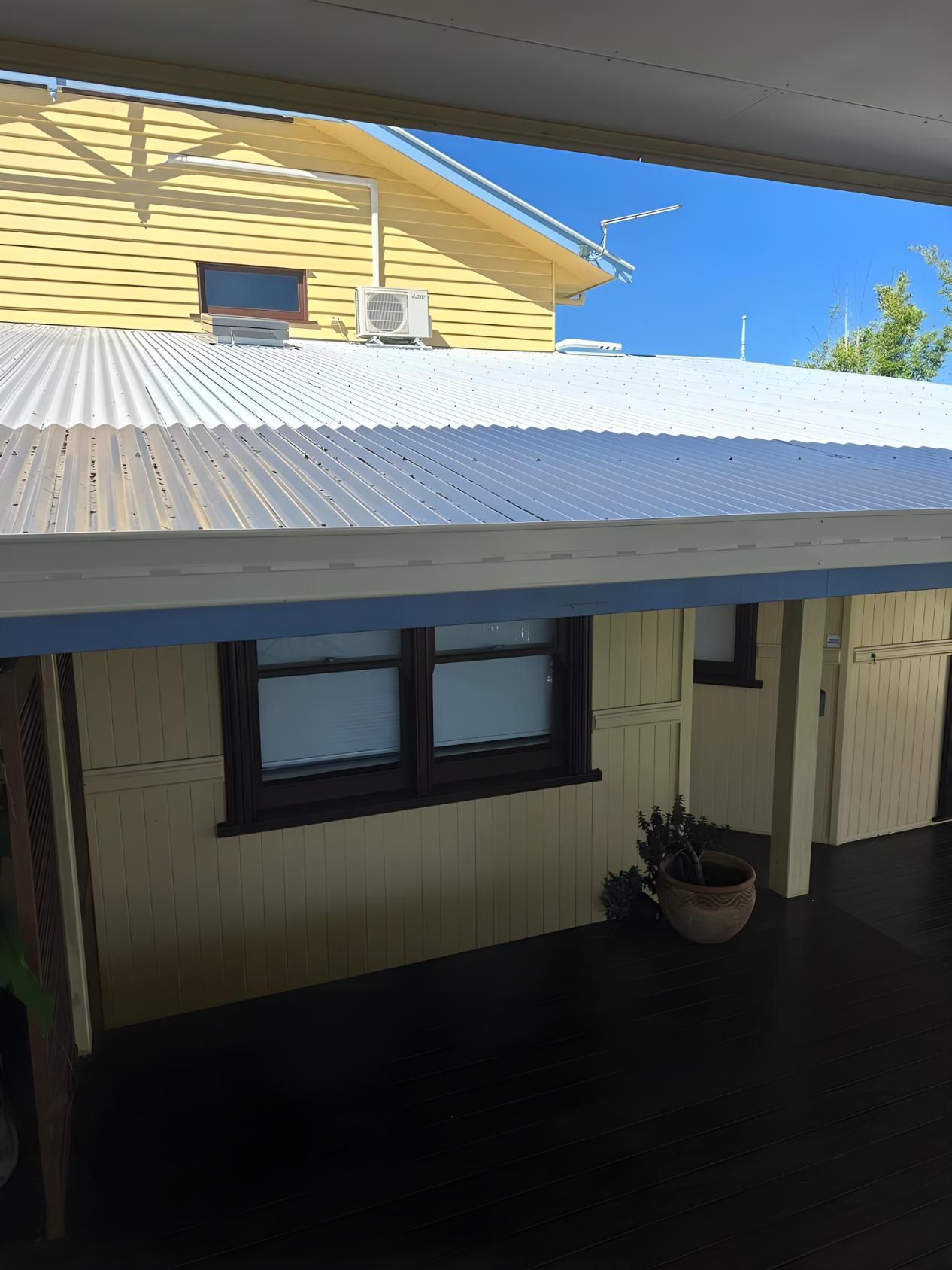 A Yellow House With A White Roof And Two Windows — Premier Roofing Solutions In Casino, NSW