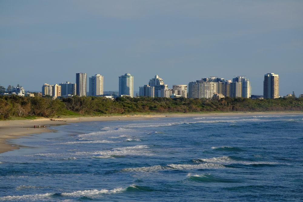 A Beach With A City Skyline In The Background And A Body Of Water In The Foreground — Premier Roofing Solutions In Tweed Heads, NSW